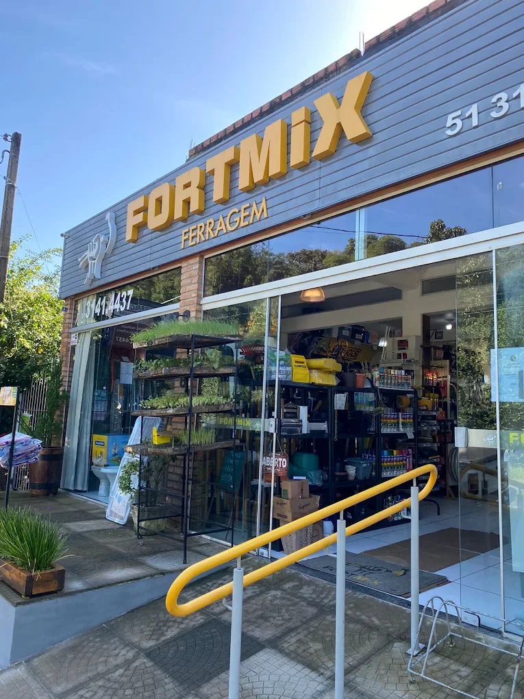 Fachada da Fortmix Ferragem, com letreiro amarelo sobre painel cinza e entrada acessível